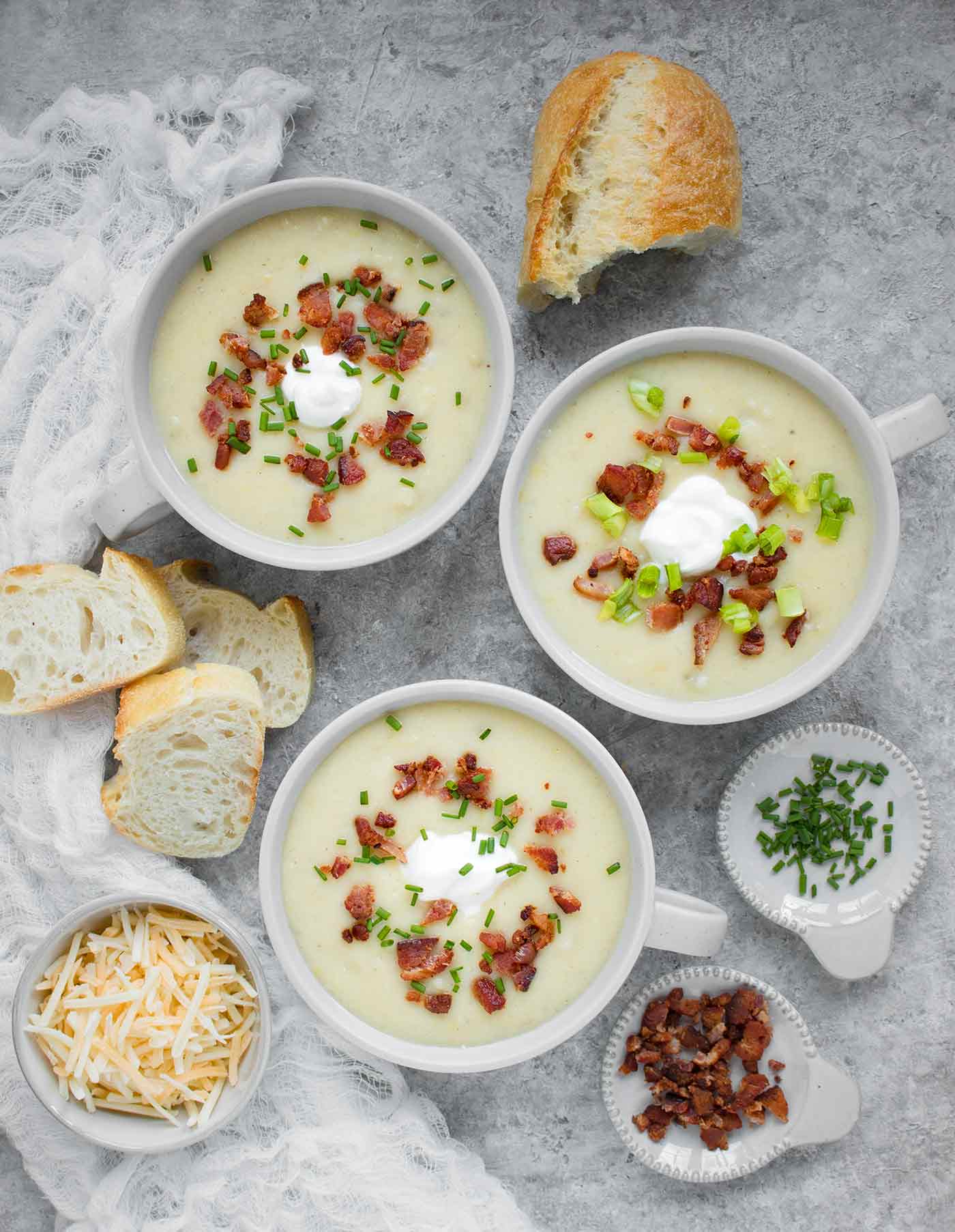 Three bowls of Instant Pot Loaded Potato Soup with bread on the side
