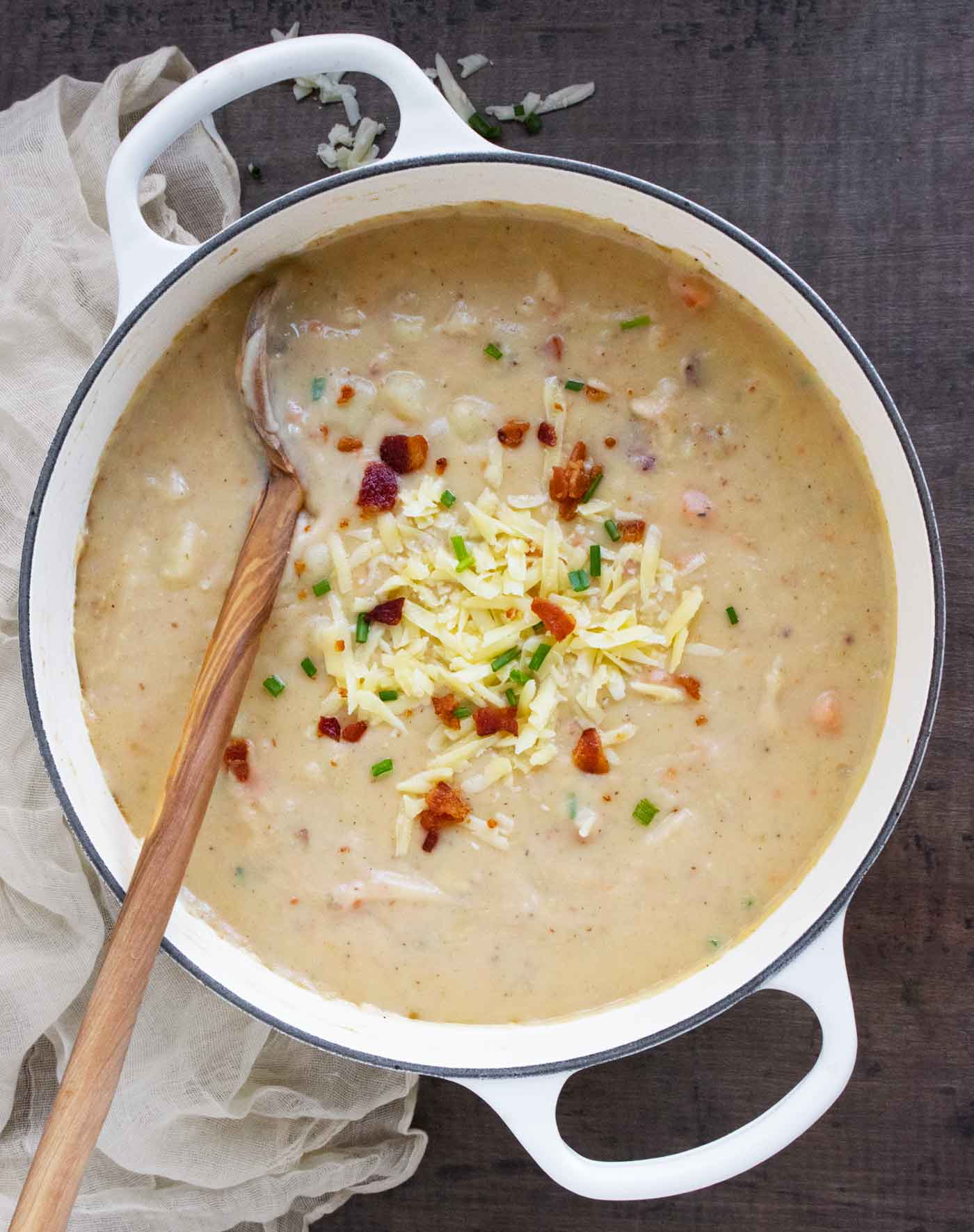 Overhead view of Irish Potato Soup in a large white Dutch Oven, with a wooden spoon.
