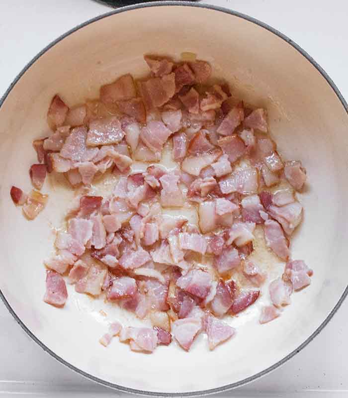 Raw bacon pieces cooking in the soup pot.