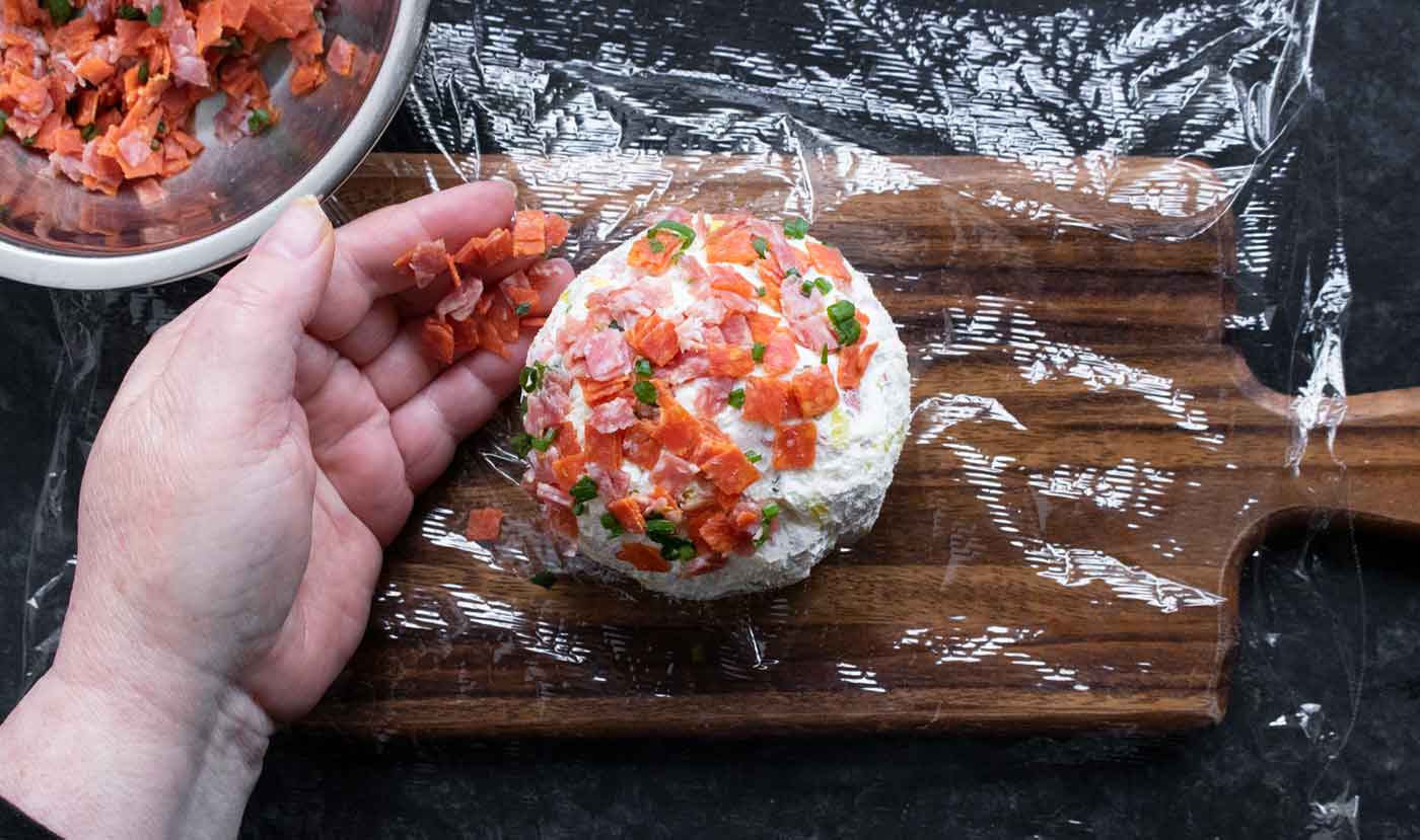 Covering the cheese ball in a mosaic of pepperoni and salami pieces.