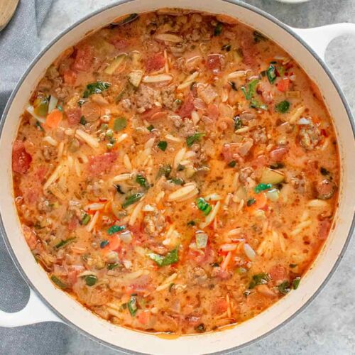 Overhead view of Italian Sausage Orzo Soup in a white Dutch oven.