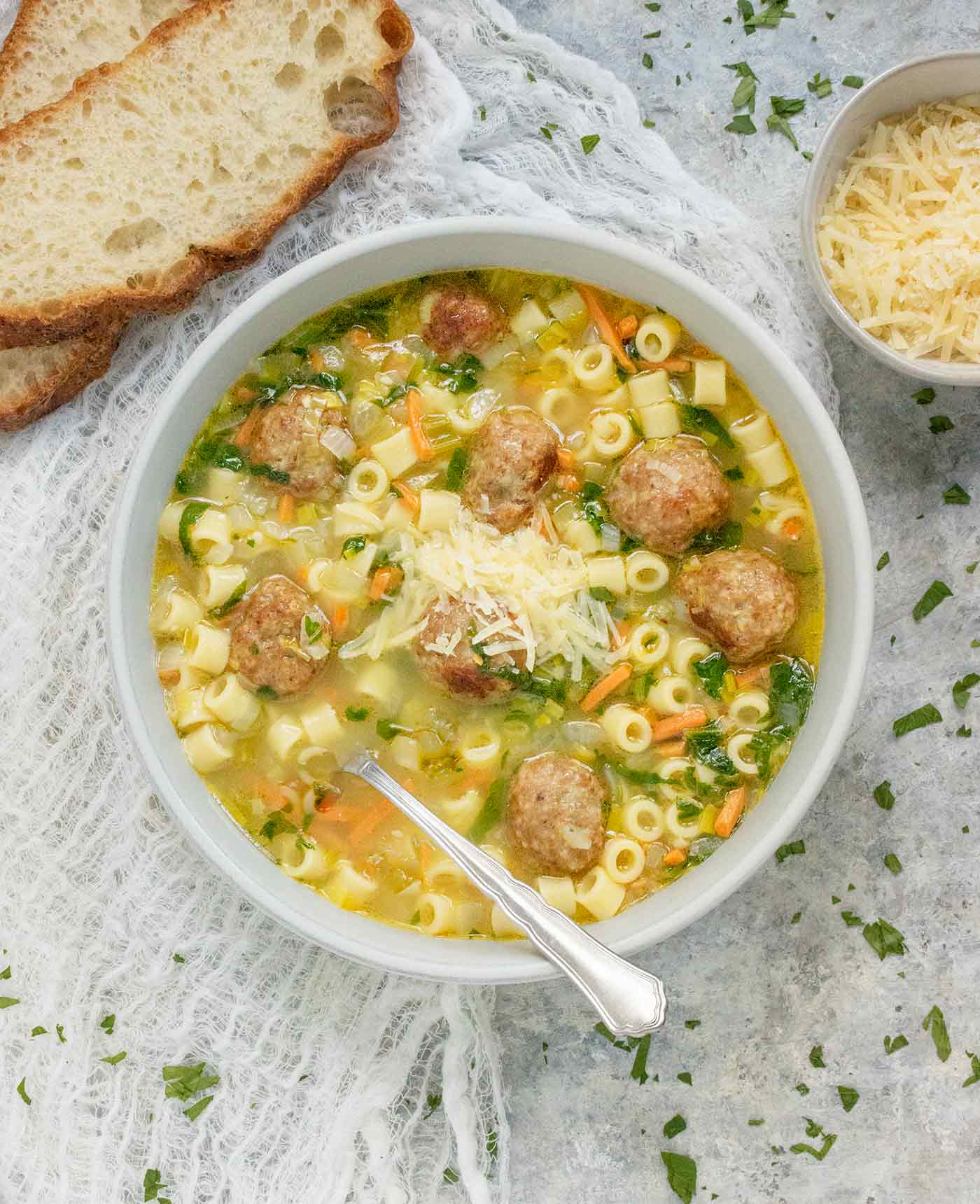 Italian Wedding Soup in a light gray bowl with a spoon.