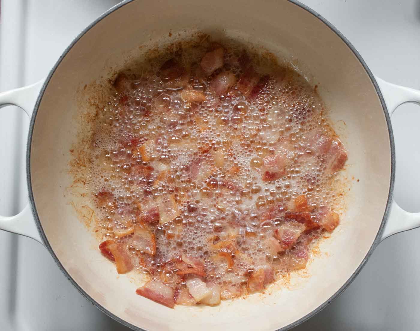 Bacon cooking in a Dutch oven.