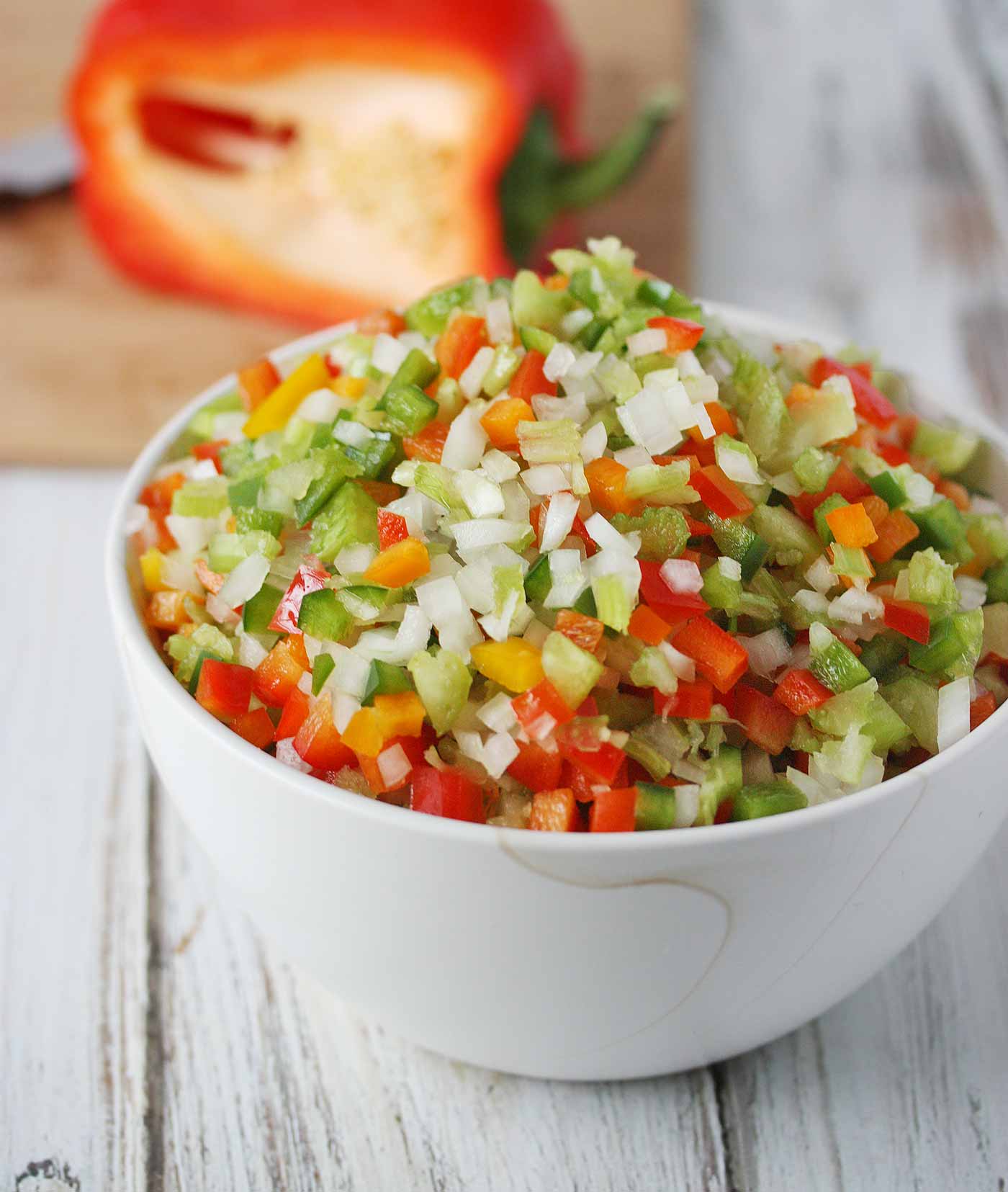 A bowl of diced Holy Trinity aromatic vegetables, including onions, celery, and red and green bell peppers.