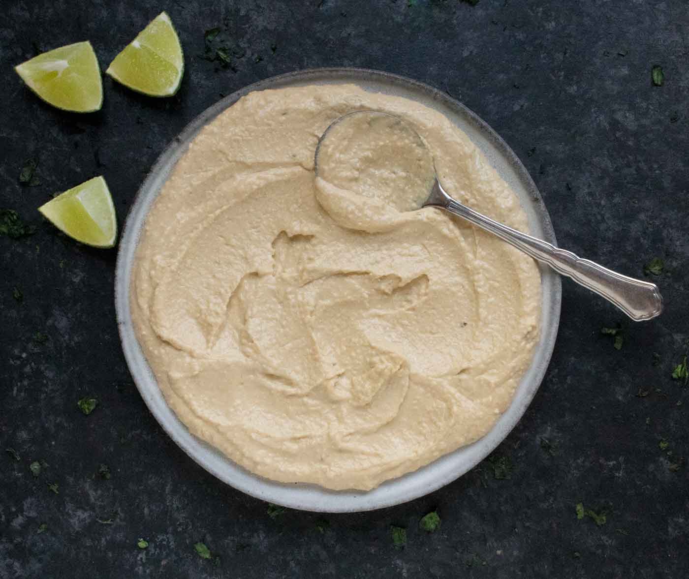Hummus spread on a plate with a spoon.