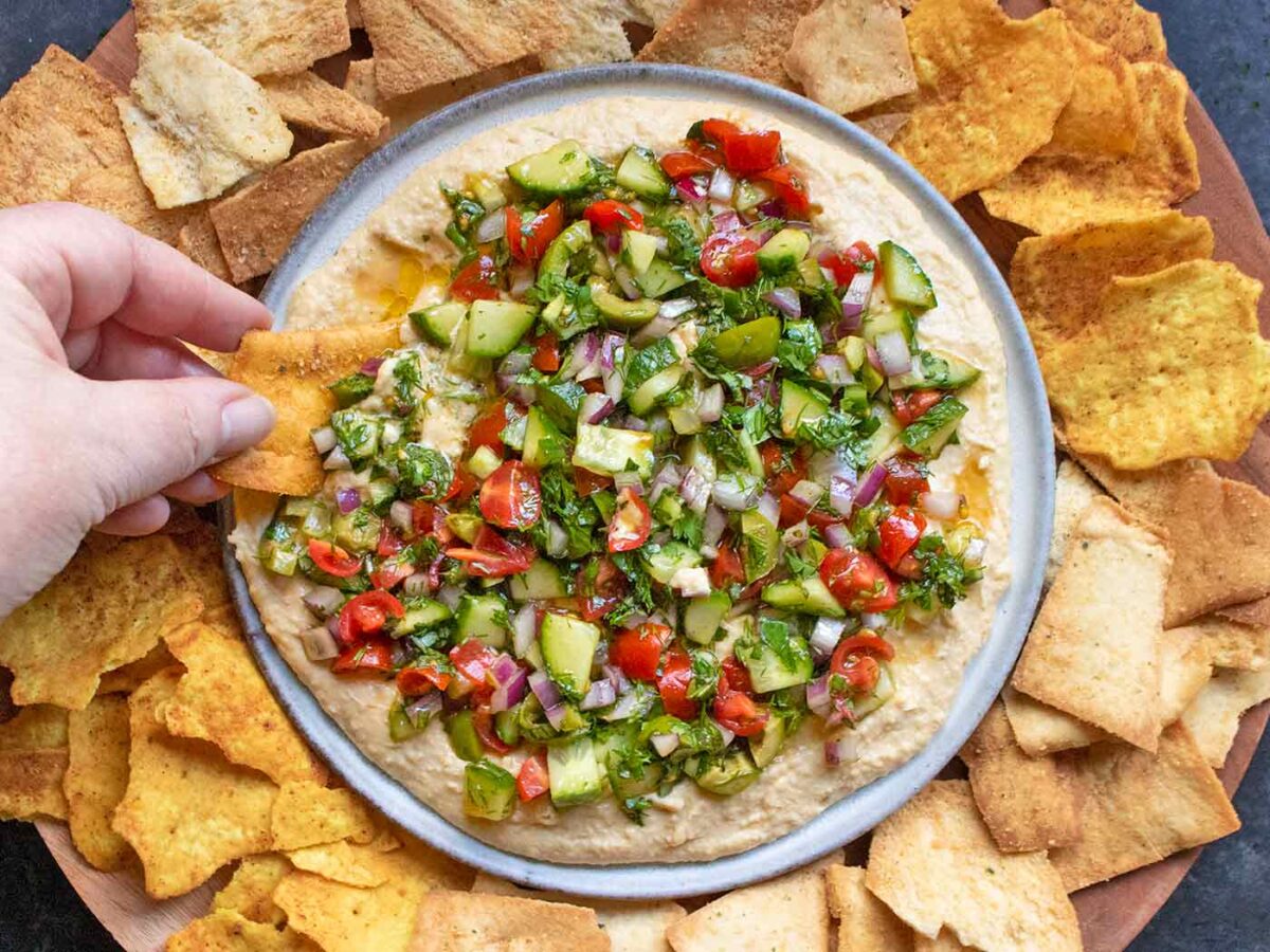 Layered Veggies & Hummus dip on a plate with a variety of crackers.