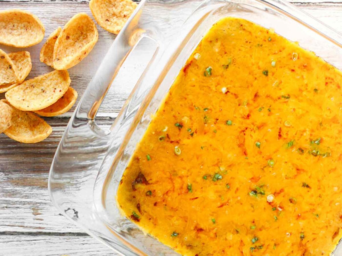 Loaded Skyline Chili Dip in a casserole dish, ready to serve, with a side of Fritos.