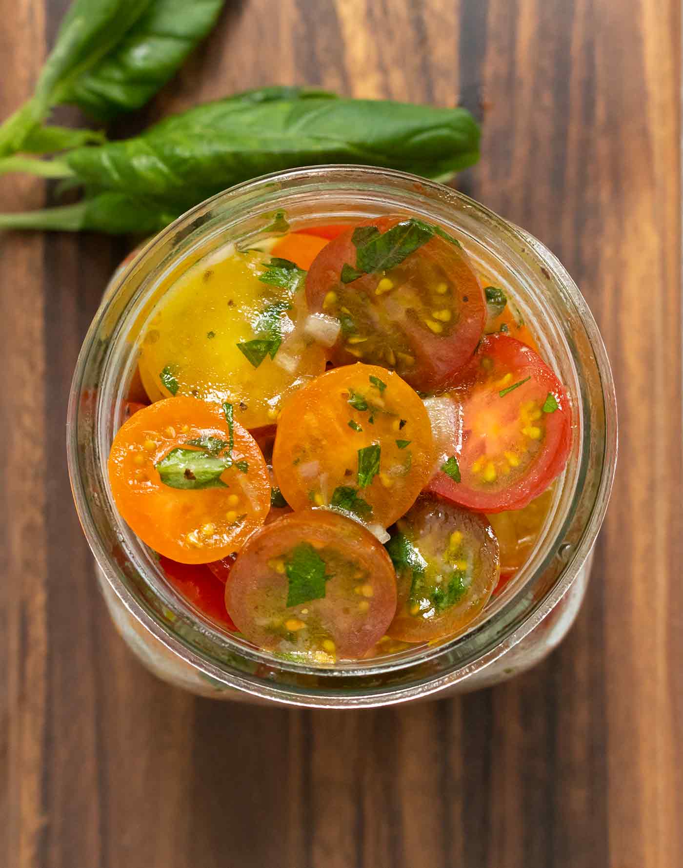 View from above of a jar of cherry tomatoes in marinade.