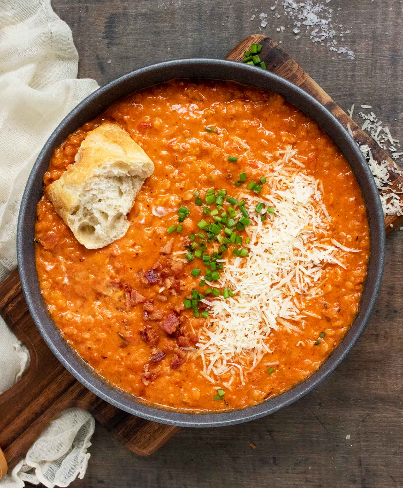 Overhead close-up of a bowl of Marry Me Red Lentil Soup with a slice of bread on top.