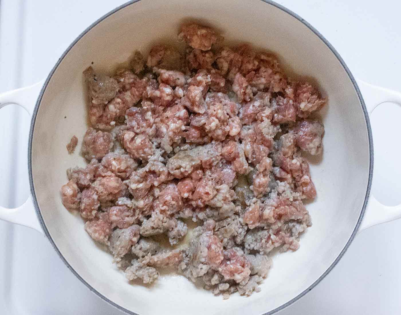 Sausage cooking in a large dutch oven.