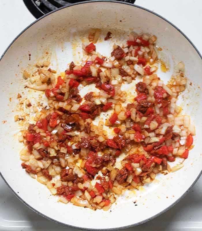 Onions, sun-dried tomatoes, and roasted red peppers sauteeing in the skillet.