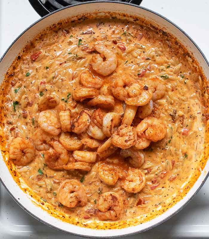 Folding in the reserved shrimp to complete the dish.