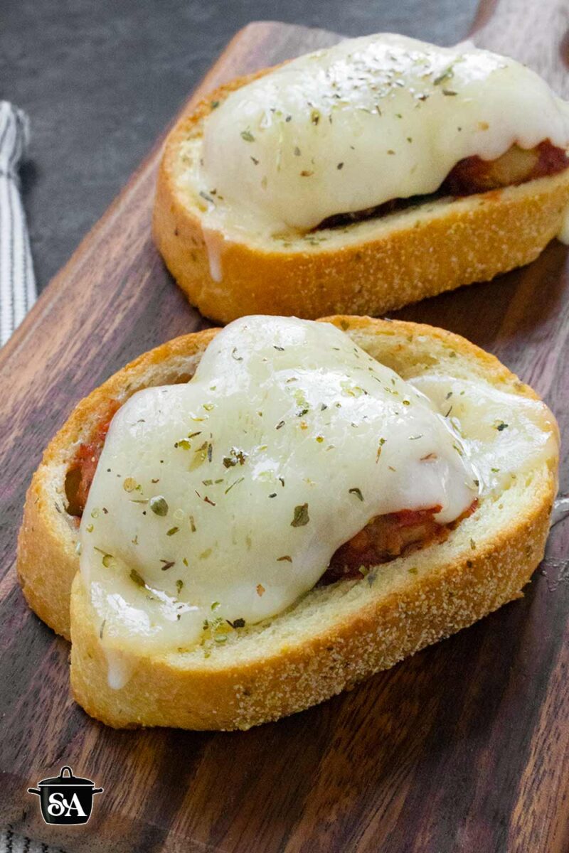 Pinterest pin image featuring two Meatballs on Texas Toast open-faced sandwiches, on a wooden board.