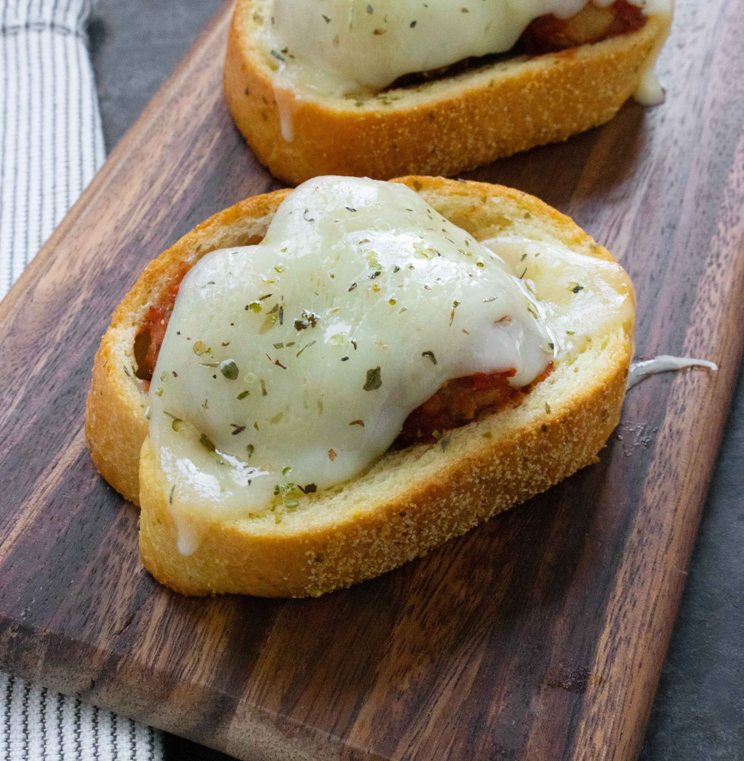 Side angled view of Meatballs on Texas Toast on a wooden board.