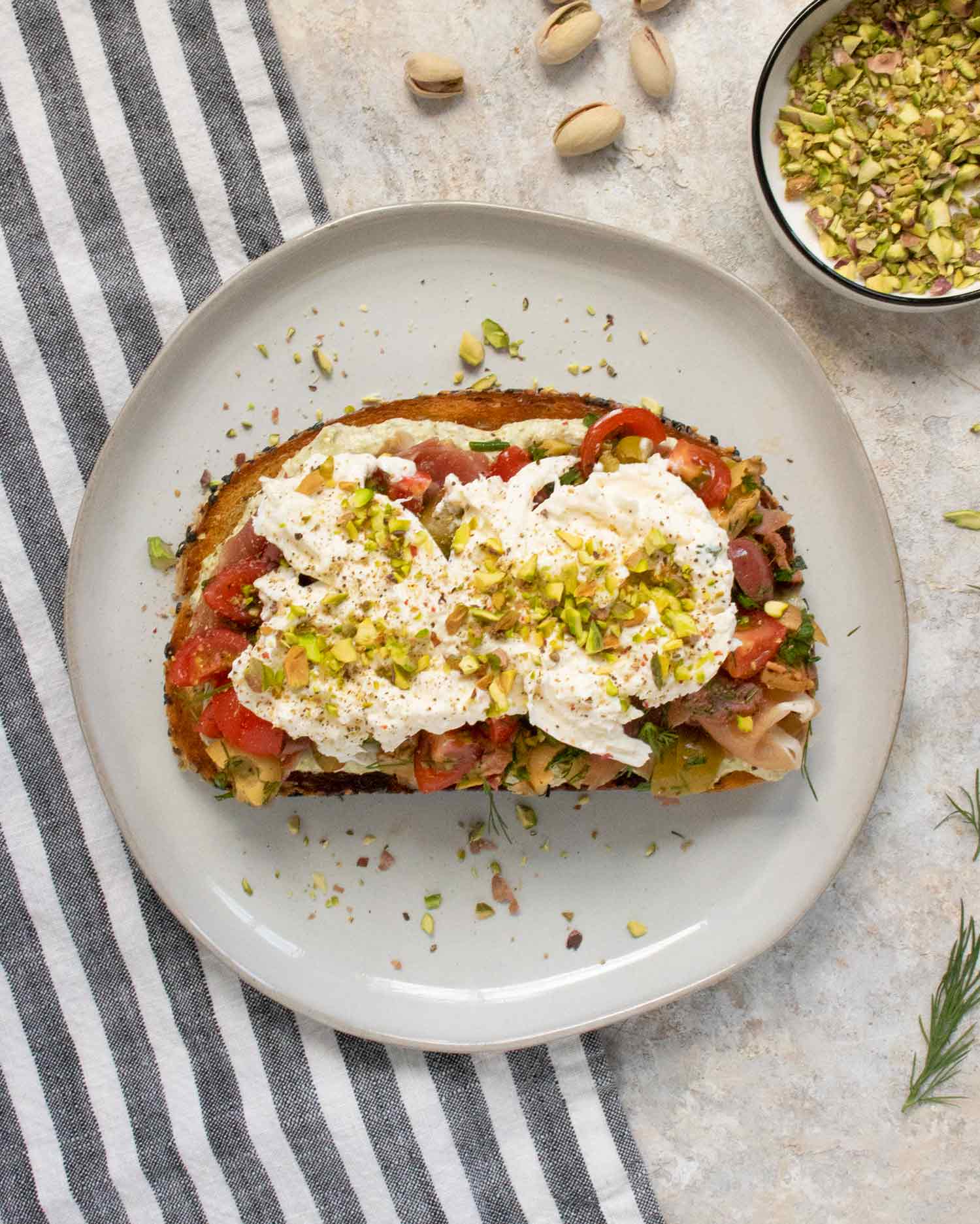 Overhead view of one Mediterranean Burrata Fried Toast with Creamy Pesto on a light gray plate.