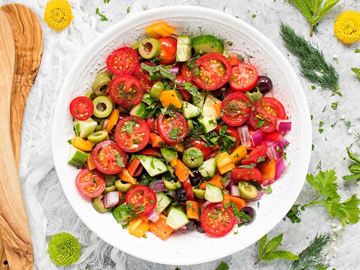 Overhead view of colorful Mediterranean Salad in a white serving bowl.
