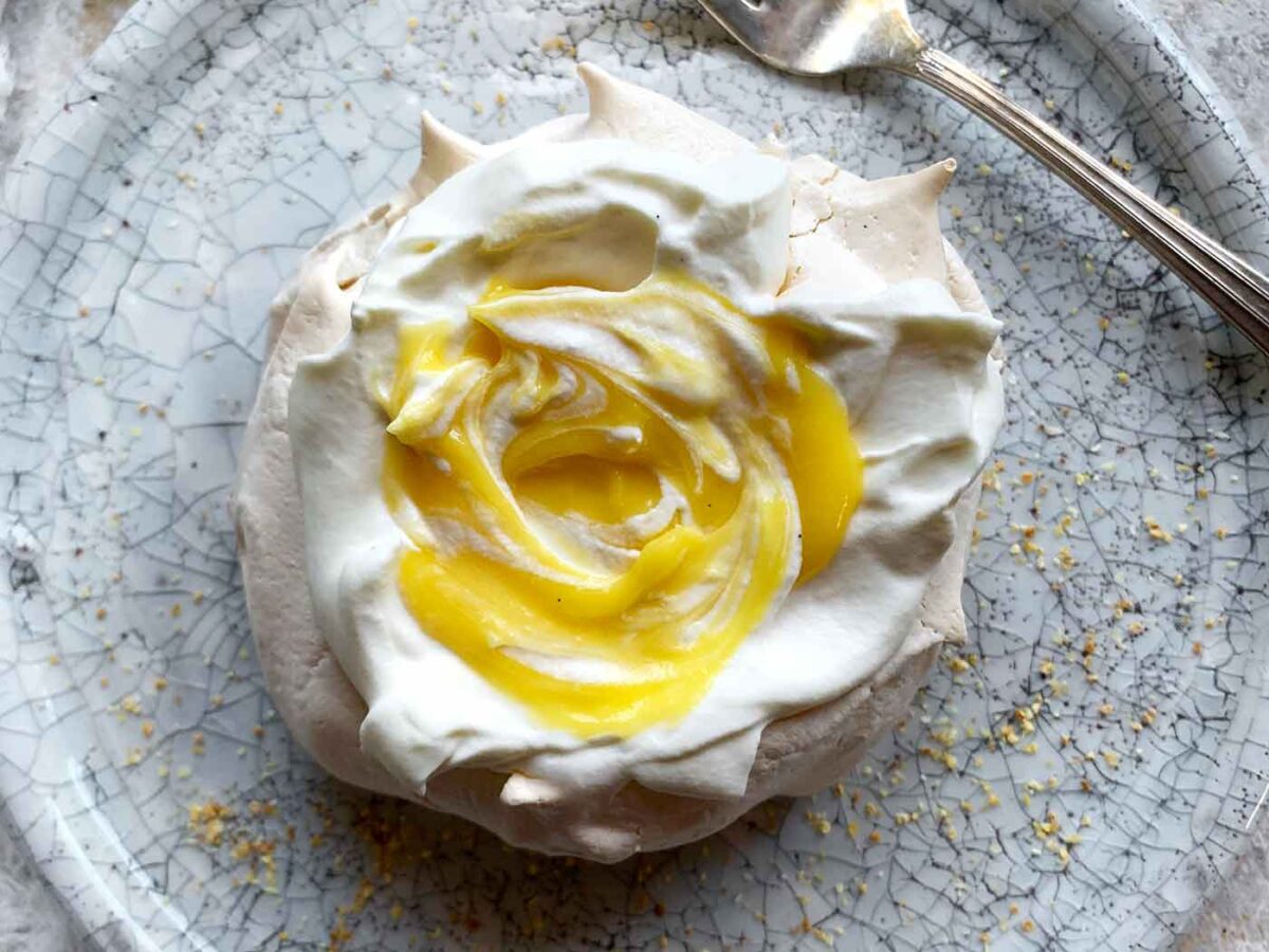 A Mini Pavlova with Tangerine Curd on a plate with a fork.