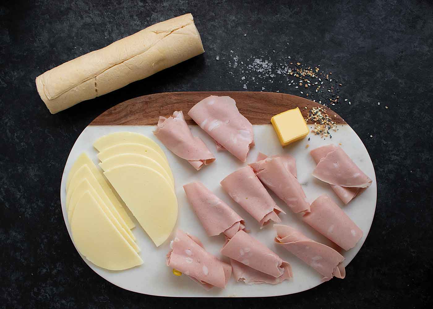 Prepped ingredients for Mortadella Stuffed Crescent Rolls on a serving board, ready to cook.