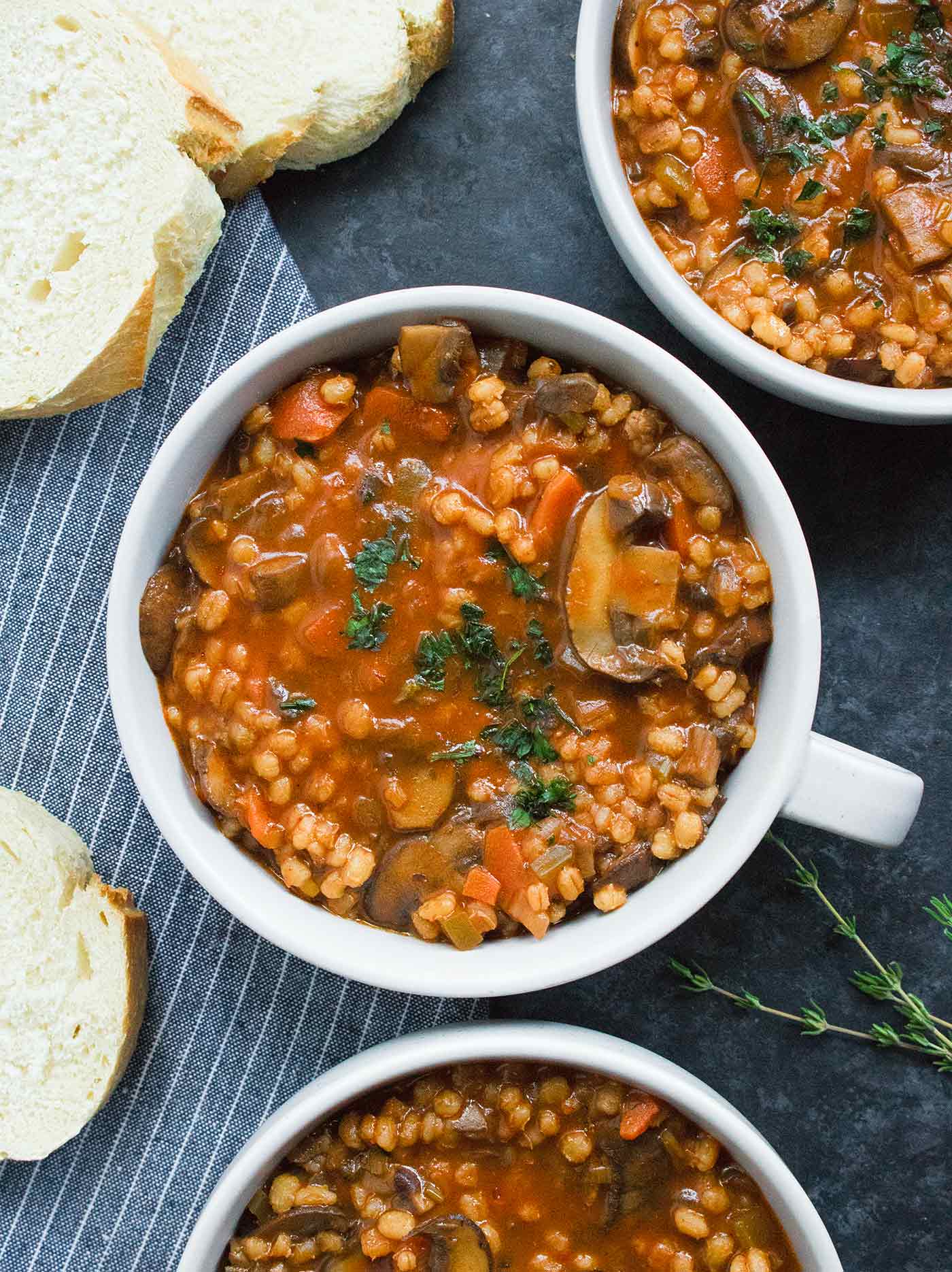 Three bowls of Mushroom Barley Soup with a side of bread