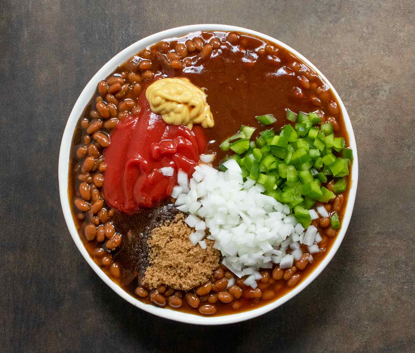 Ingredients for Oven-baked Canned Baked Beans in a mixing bowl.