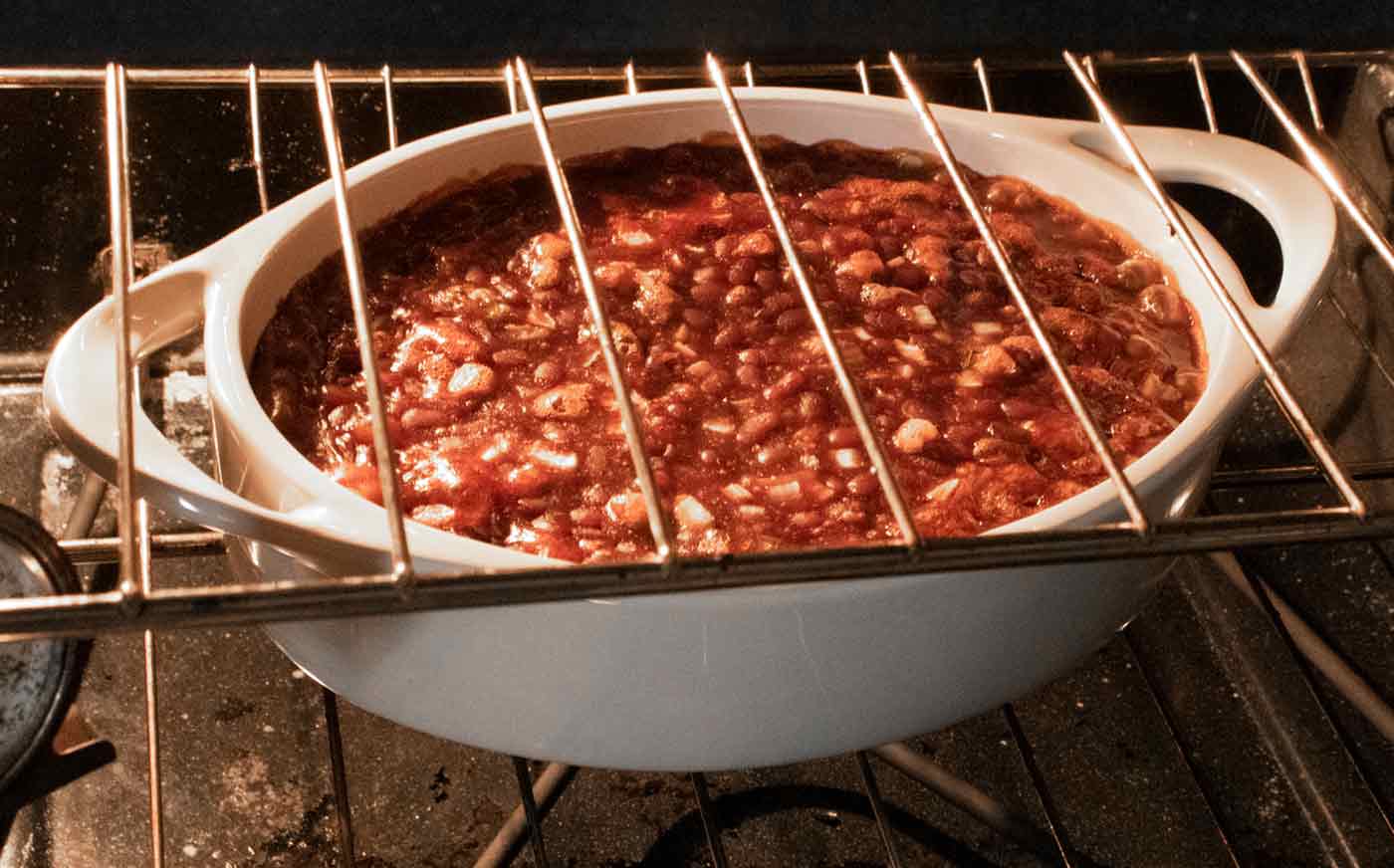Baked beans in a white baking dish in the oven.