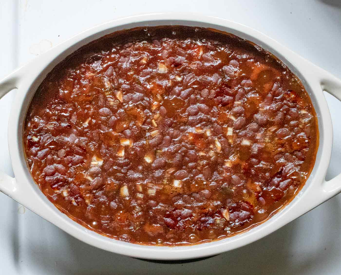 Overhead view of the finished Oven-baked Canned Baked Beans resting on the stove prior to serving.