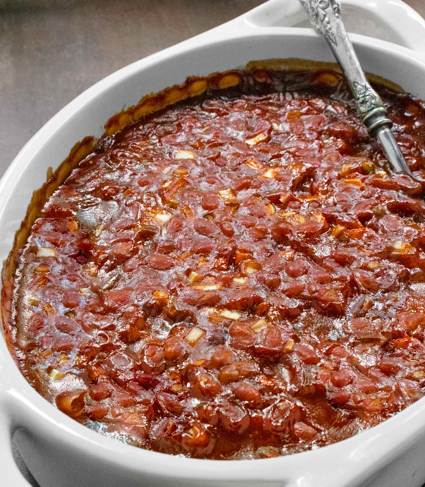 Side angle view of baked beans in an oval baking dish.