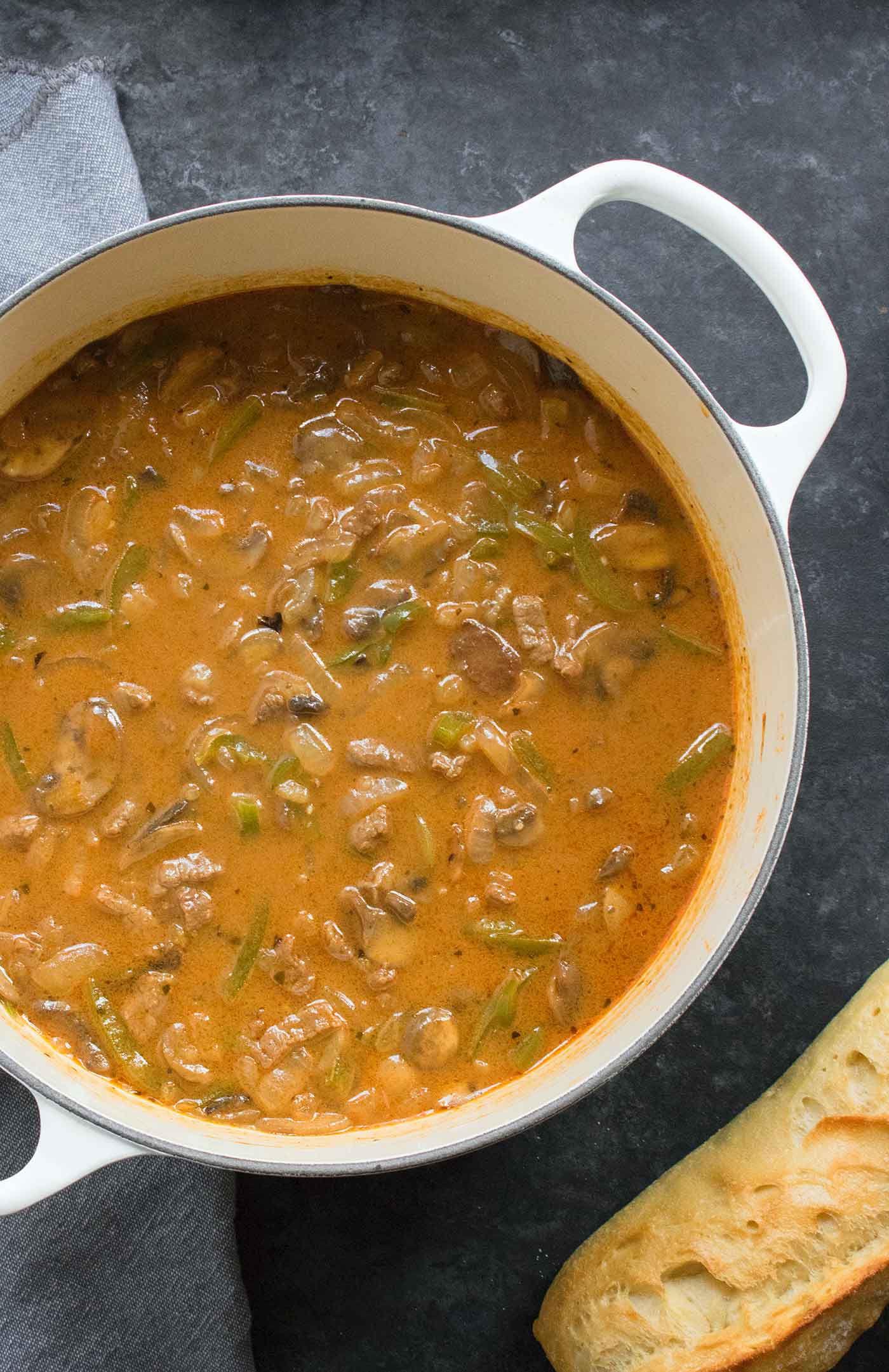 The finished soup in a large white Dutch oven, with a loaf of crusty baguette on the side