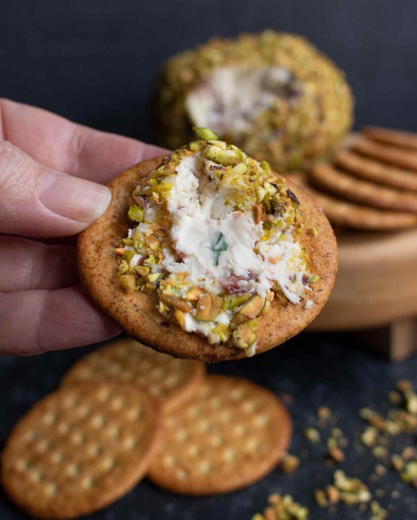 Close-up of pistachio cranberry cheese ball spread on a cracker.