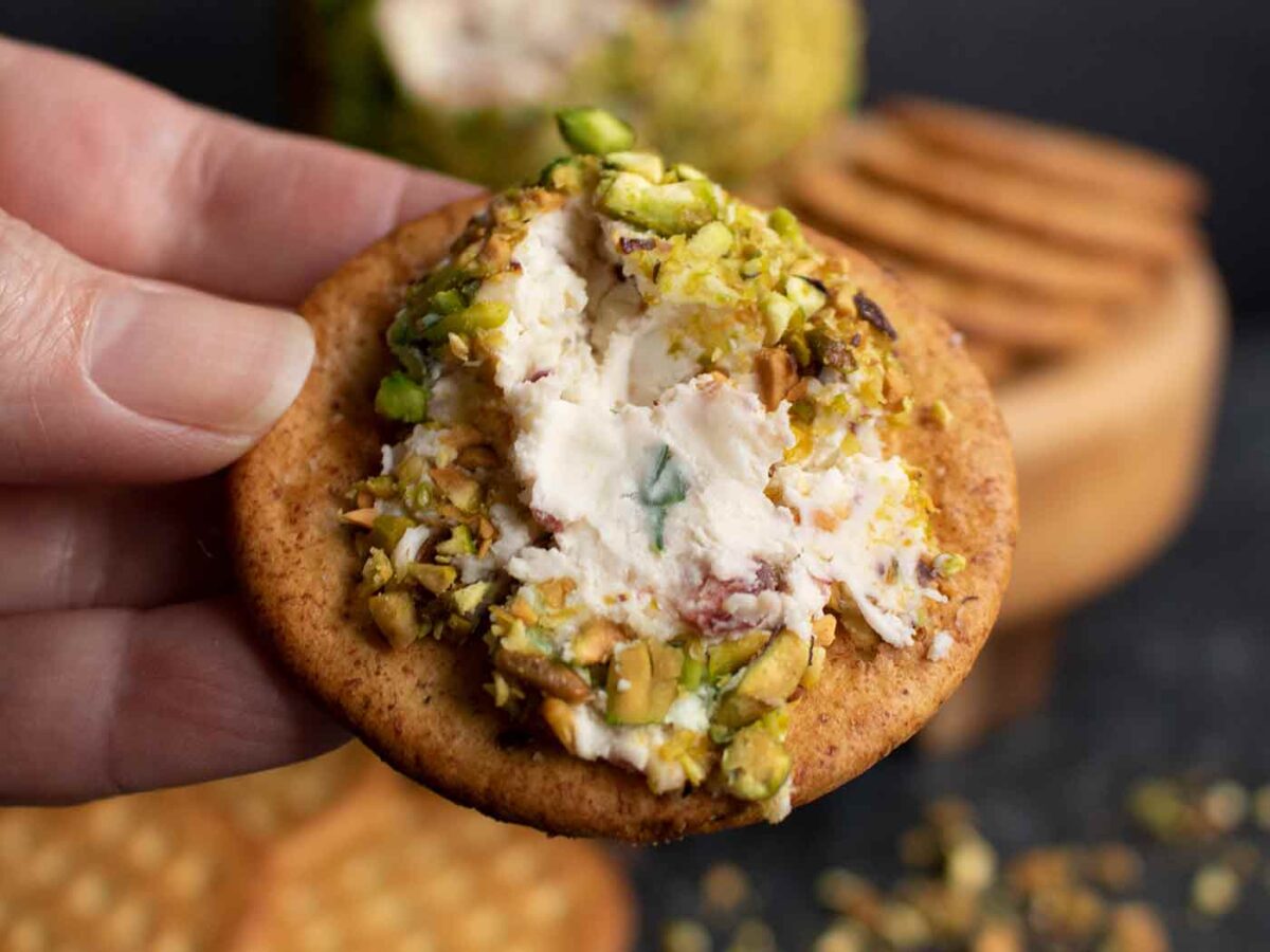 Pistachio Cranberry Cheese Ball spread on a round cracker.