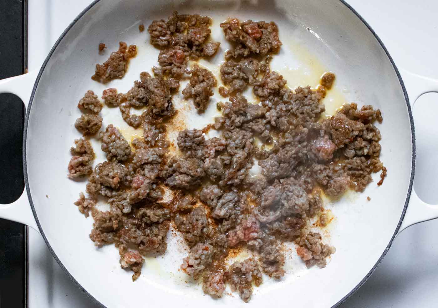 Italian sausage browning in a braiser.