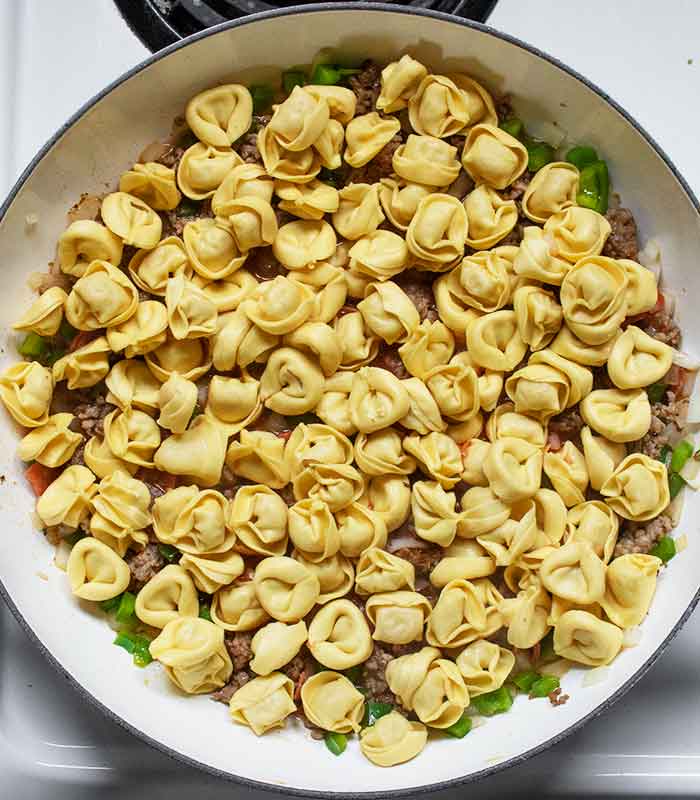 Layering the refrigerated tortellini over the sausage mixture.