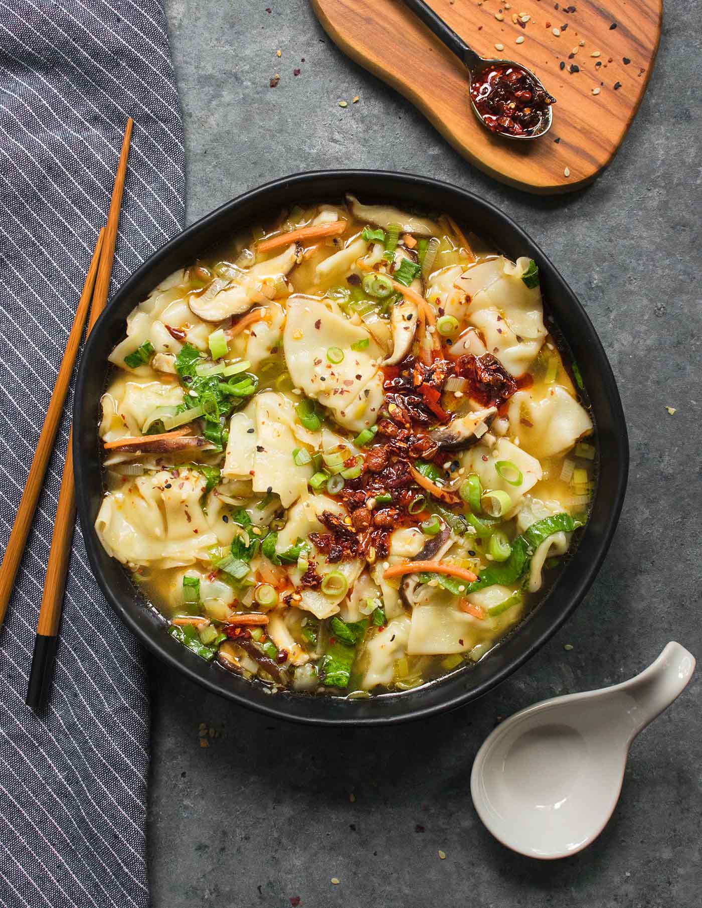 A black soup bowl filled with Potsticker Soup, with chopsticks on the side.