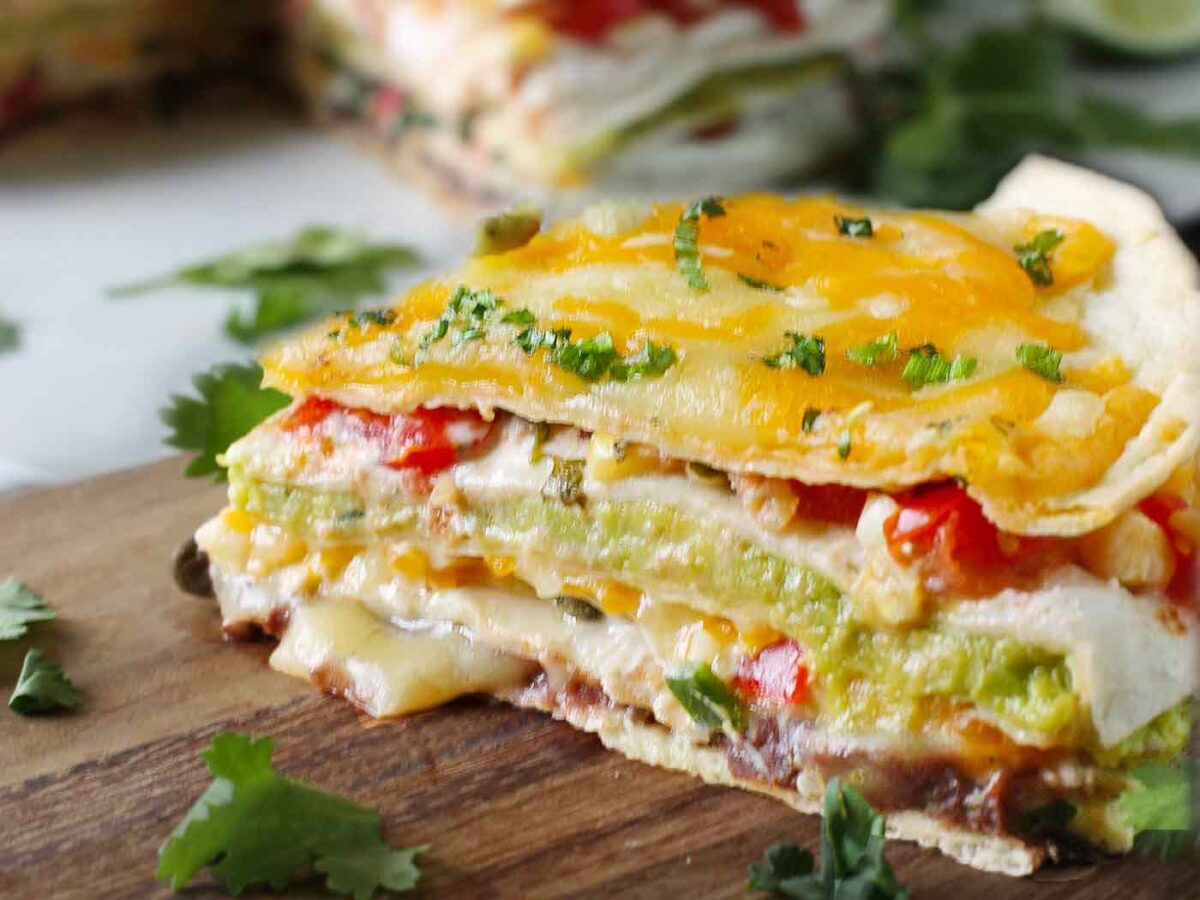 A slice of quesadilla pie on a wooden cutting board.
