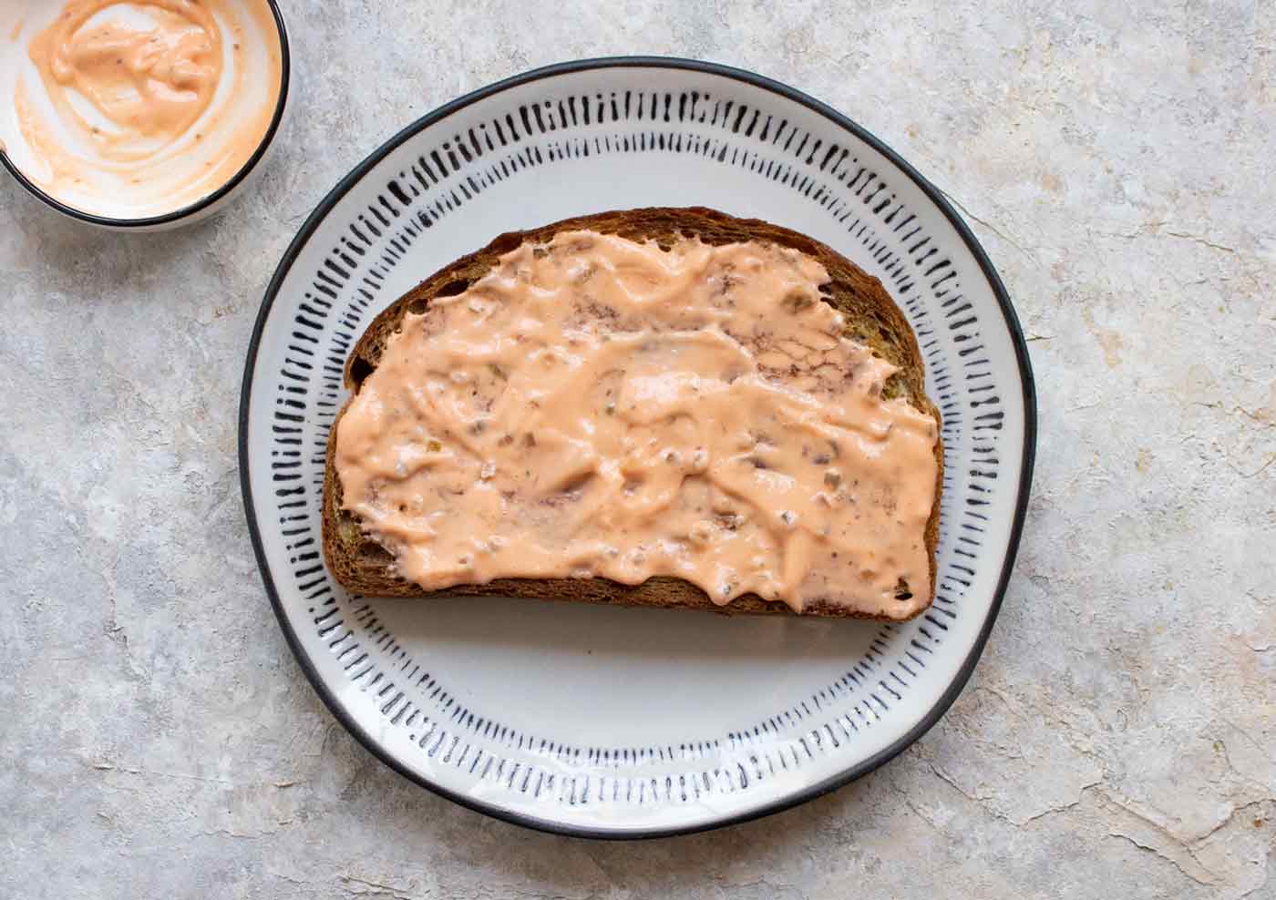 A slice of marble rye bread on a plate with Thousand Island dressing.
