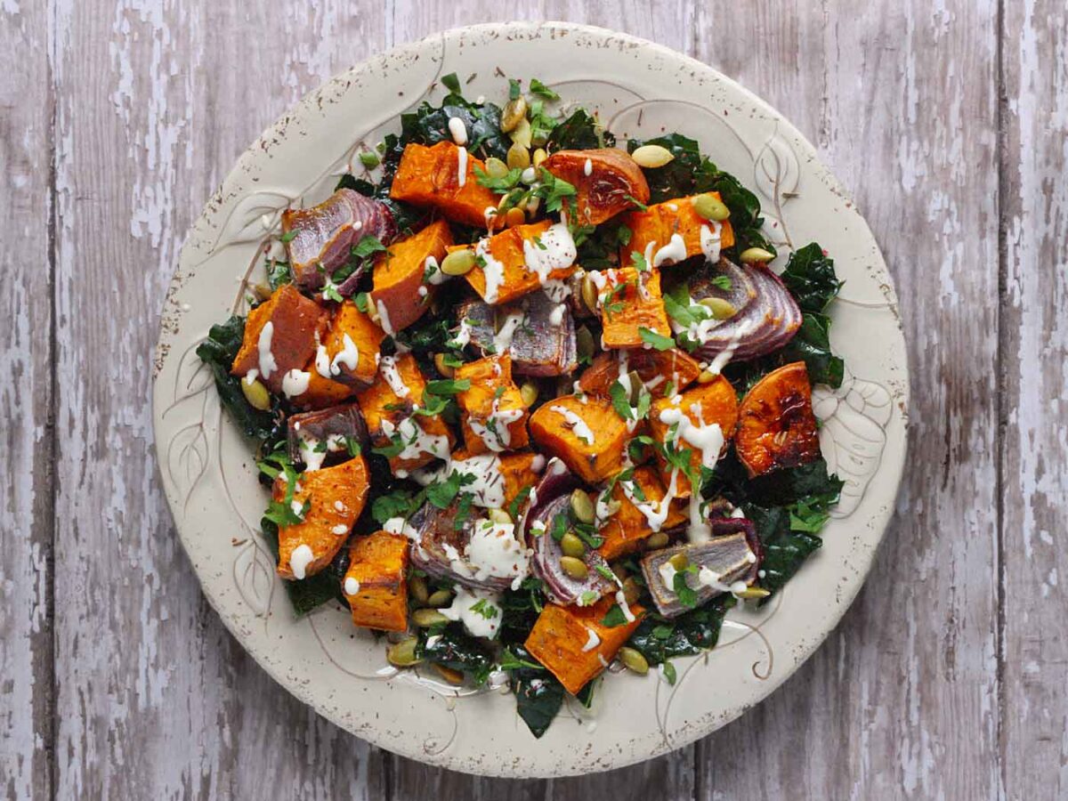 A plate of roasted sweet potatoes with greens and a tahini drizzle.