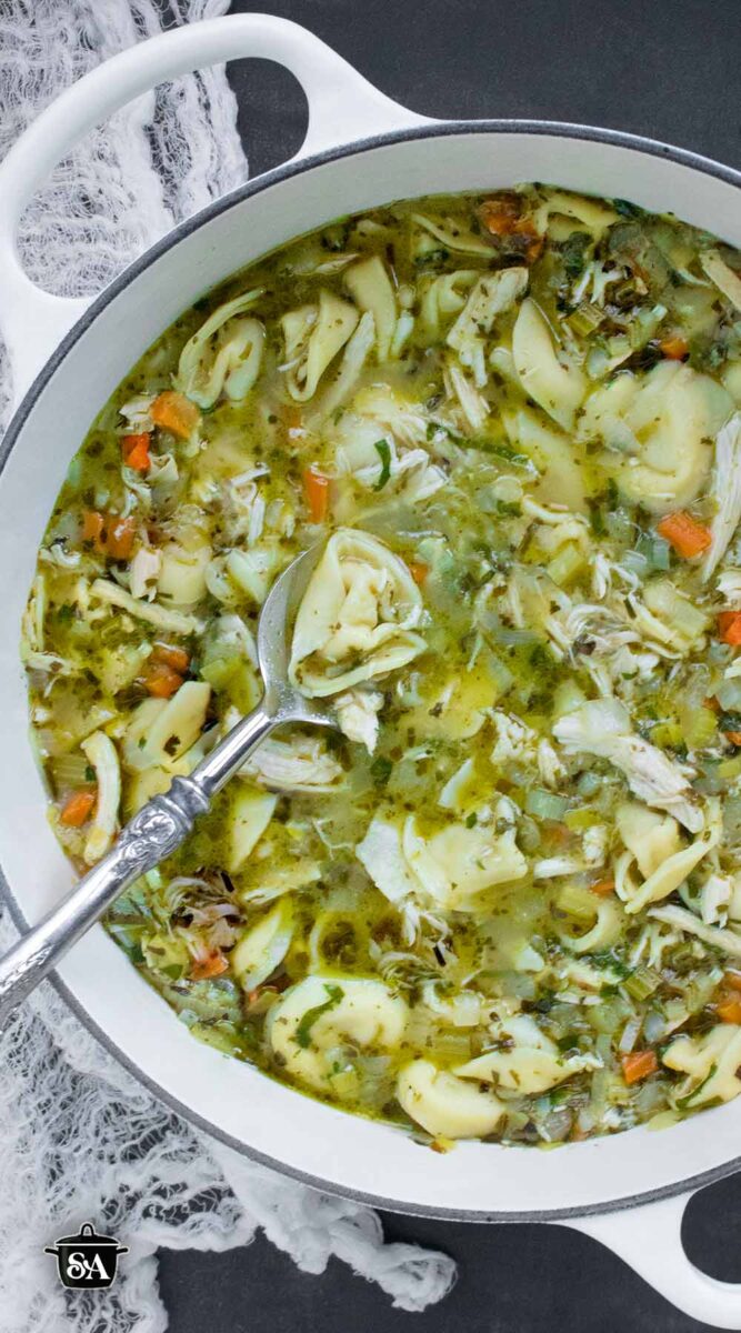 Pinterest pin image showing an overhead view of Rotisserie Chicken Tortellini Soup in a large white Dutch oven.