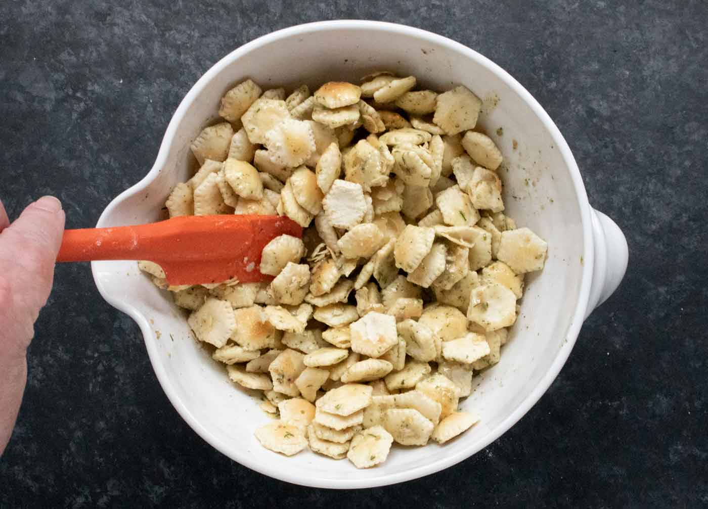 Mixing the seasoned butter into the crackers.