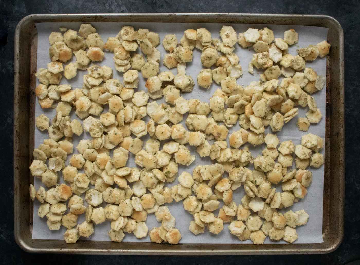 Seasoned Oyster Crackers spread out on a baking sheet, ready to bake.