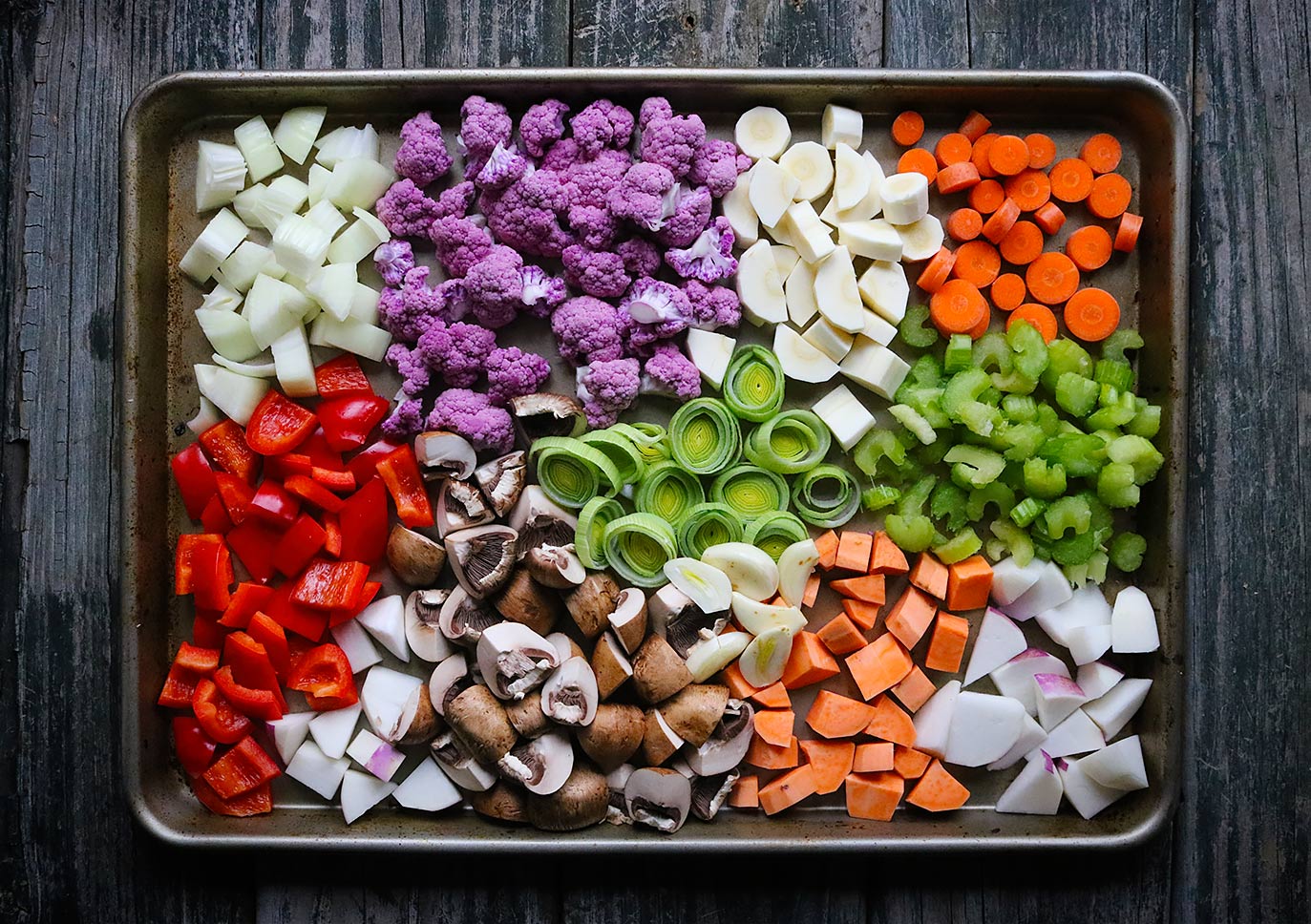 A rainbow of healthy vegetables on a sheet pan, ready to roast.