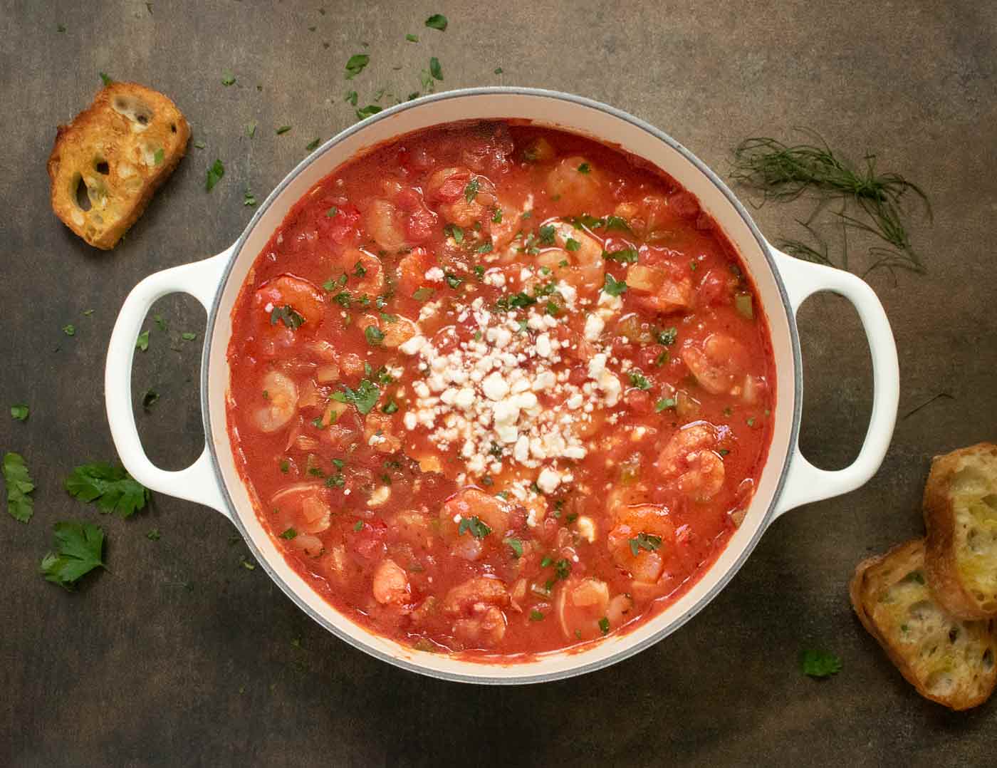 Overhead view of Shrimp Saganaki Soup in a white Dutch Oven.