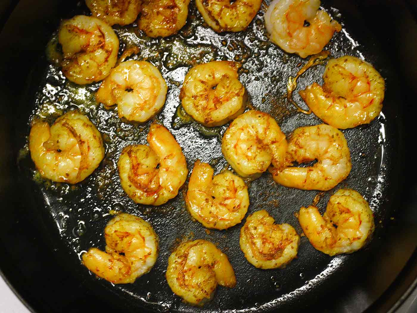 Curried shrimp cooking in a cast iron skillet