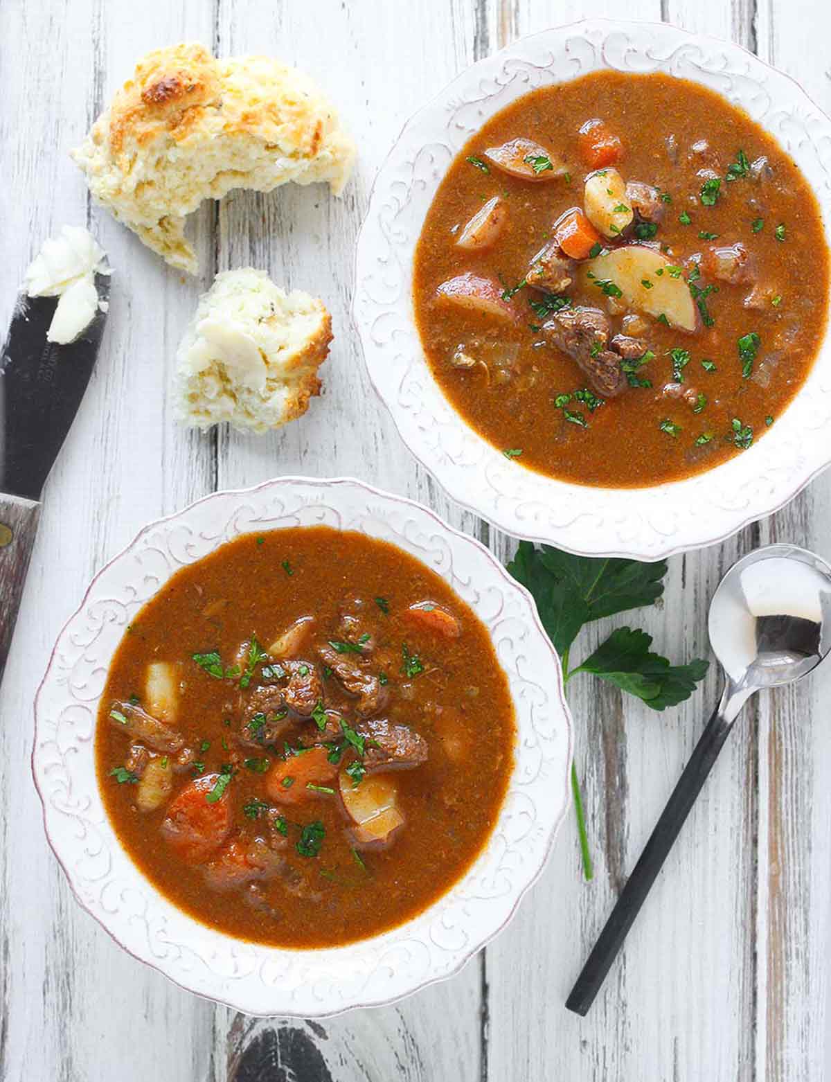 Two bowls of Guinness Beef Stew with a side of buttered biscuits