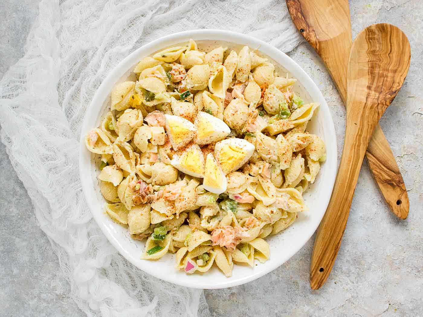 Smoked Salmon Pasta Salad in a white serving bowl with two wooden serving spoons