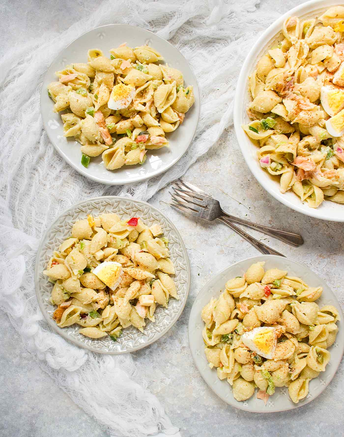 Three plates of Smoked Salmon Pasta Salad, next to the serving bowl