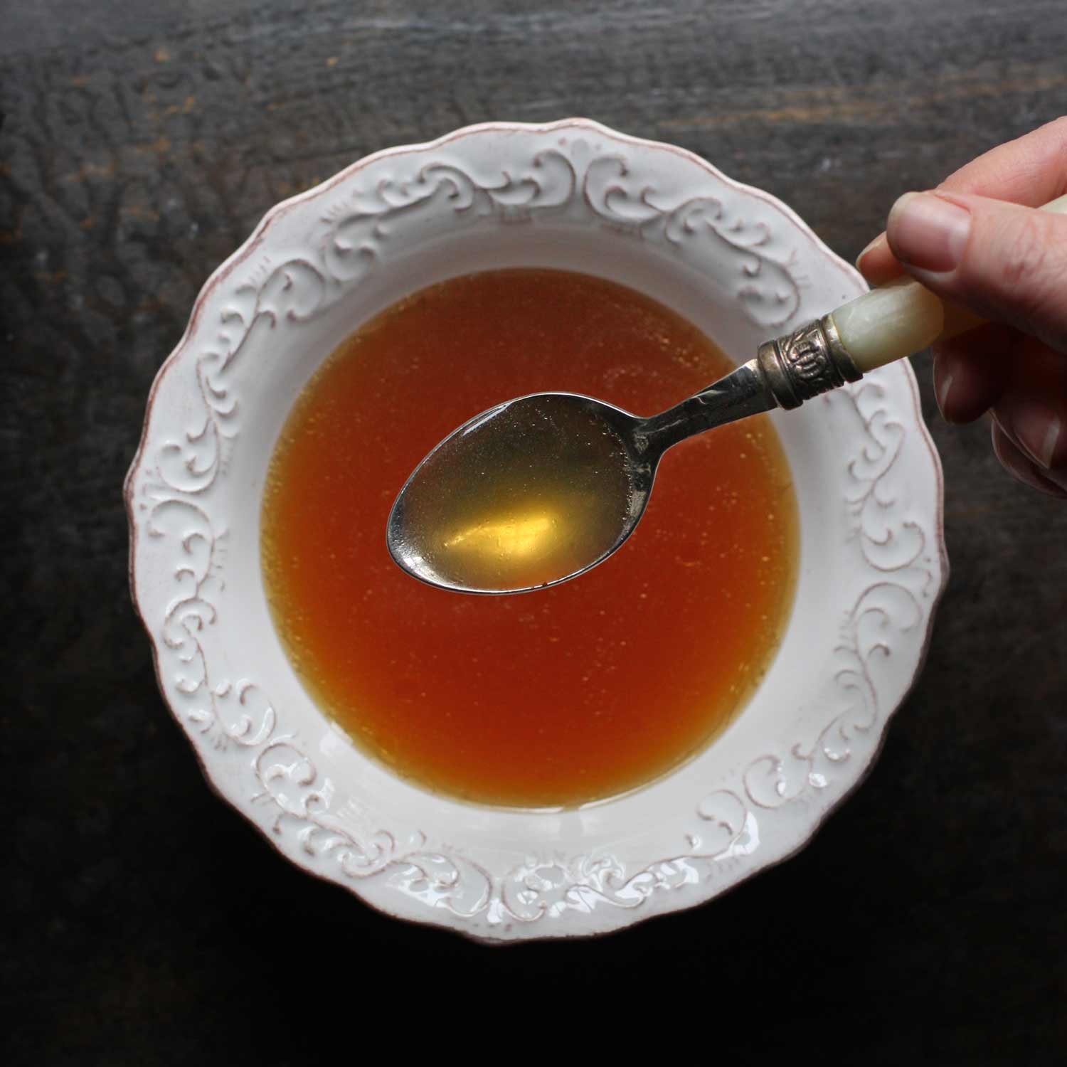 Beef consomme in a white bowl with a spoon.
