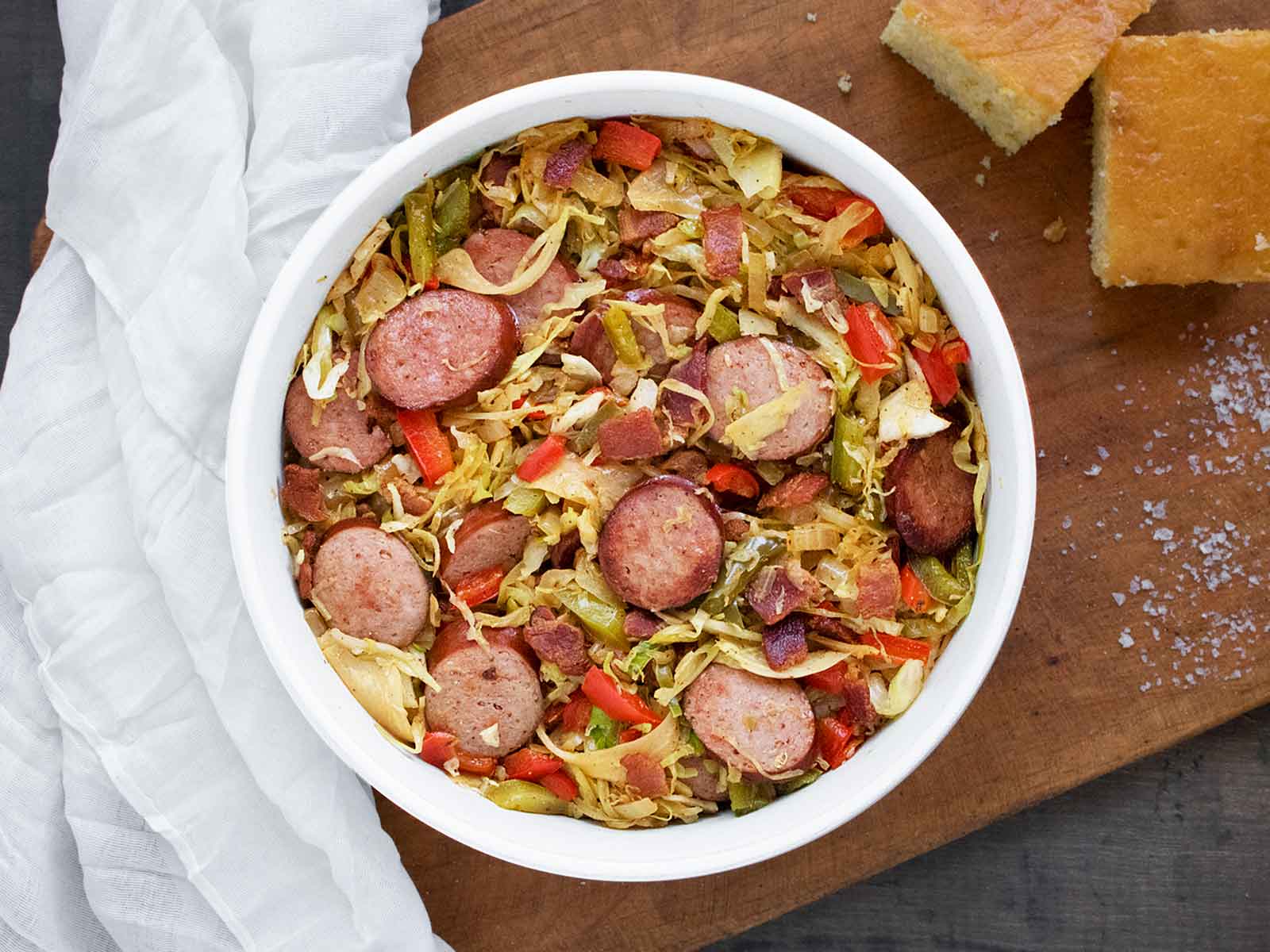 A bowl of Southern Fried Cabbage on a wooden serving board with cornbread.