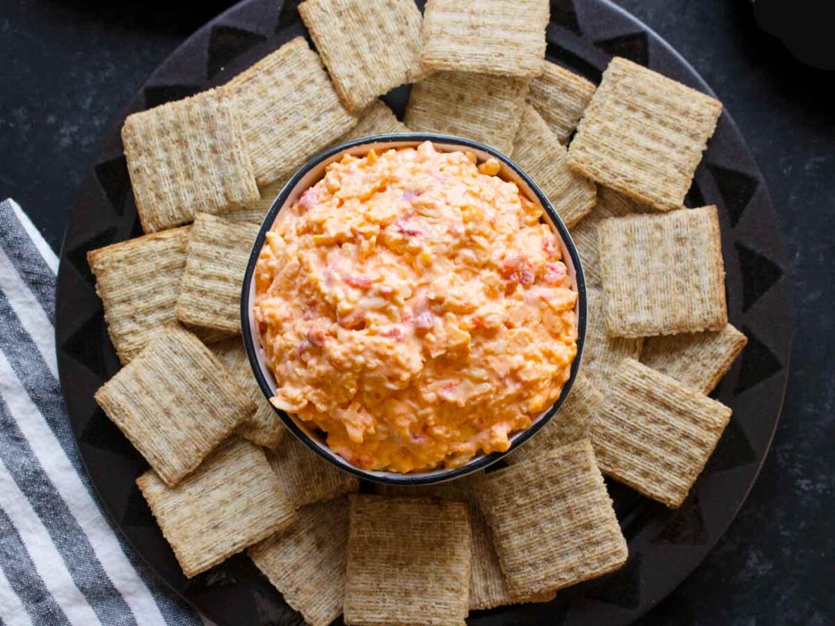 A bowl of Spicy Pimento Cheese surrounded by crackers.