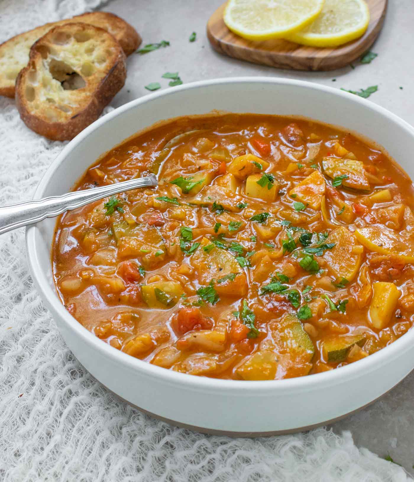 Side angled view of Summer Cabbage Soup in a bowl with a spoon.