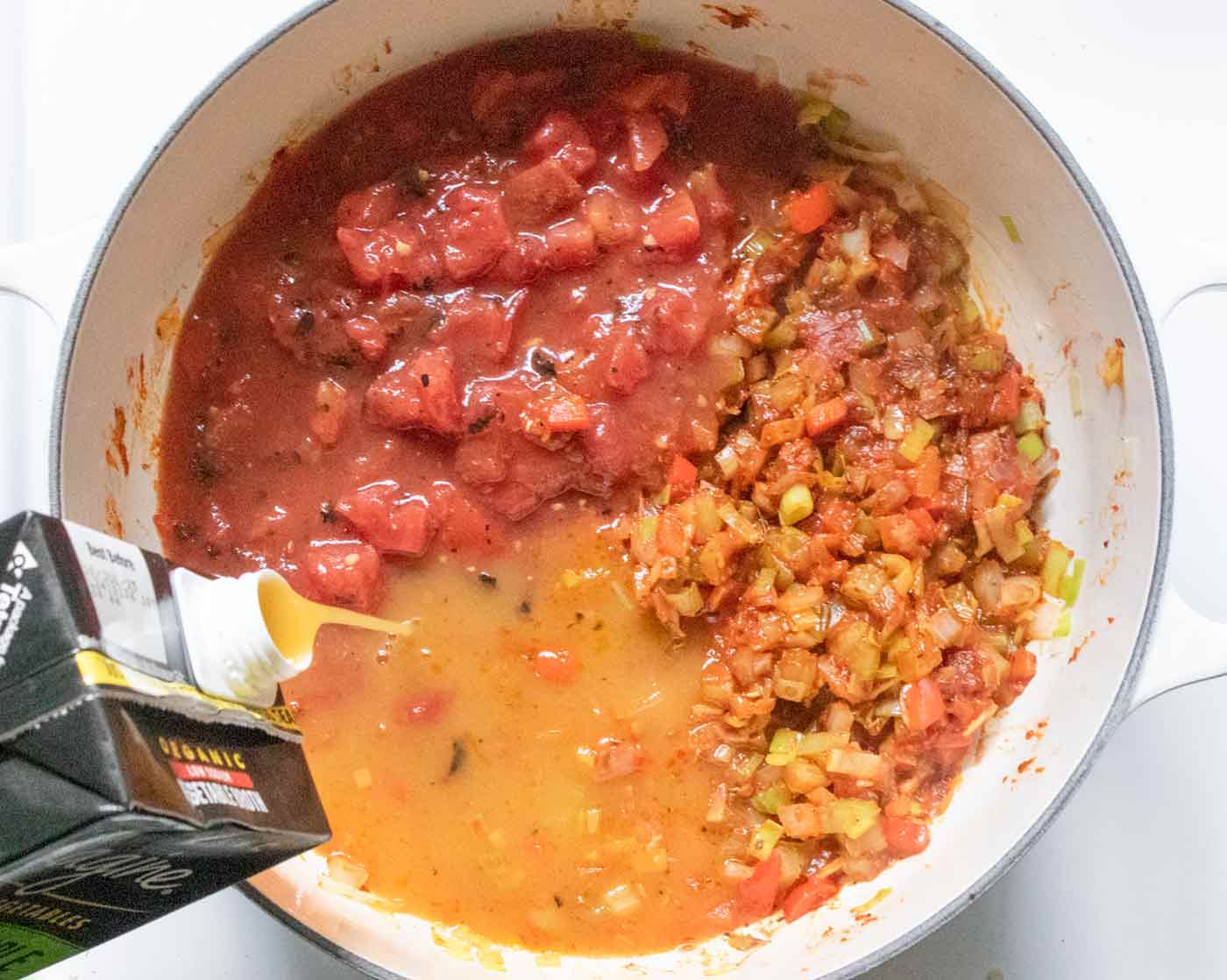 Adding the tomatoes and liquids to create the soup base.